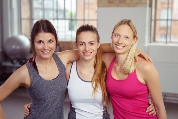 Drei lächelnde Freunde im Fitnessstudio — Stockfoto