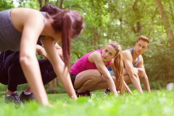 Good looking athletes squat in the green grass — Stock Photo, Image