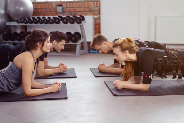 Hombres y mujeres haciendo ejercicio en esteras de yoga en estudio — Foto de Stock
