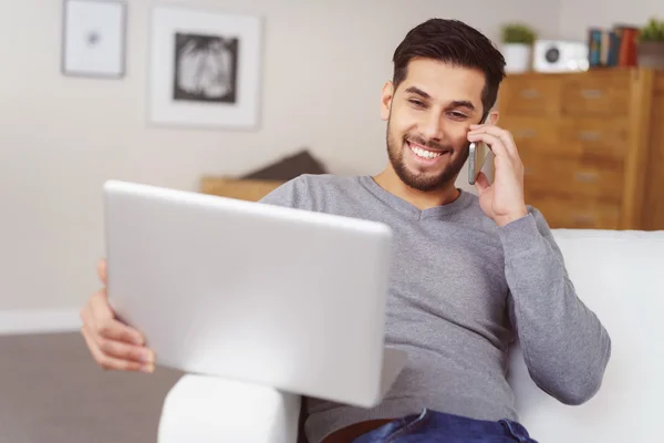 Jeune homme souriant alors qu'il discute sur un mobile — Photo