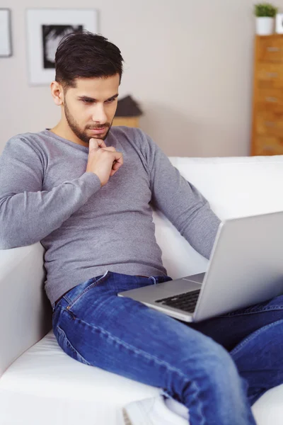 Thoughtful young man working on a laptop — Stock Photo, Image