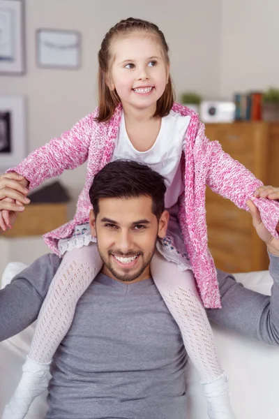 Menina feliz sentada em seus ombros pais — Fotografia de Stock