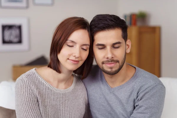 Jovem casal sentado junto com os olhos fechados — Fotografia de Stock