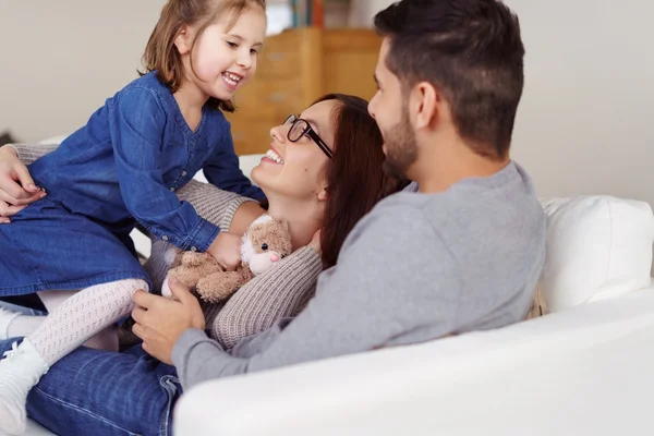 Девочка играет на диване с родителями — стоковое фото