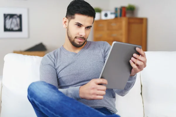 Bello uomo barbuto seduto sul divano con tablet — Foto Stock