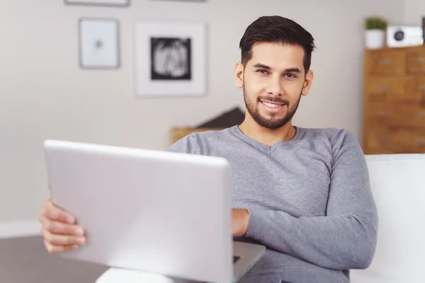 Jeune homme barbu souriant relaxant sur un canapé — Photo