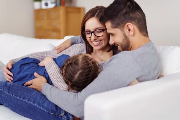 Fröhliche Eltern, die ihr kleines Mädchen auf dem Schoß halten — Stockfoto