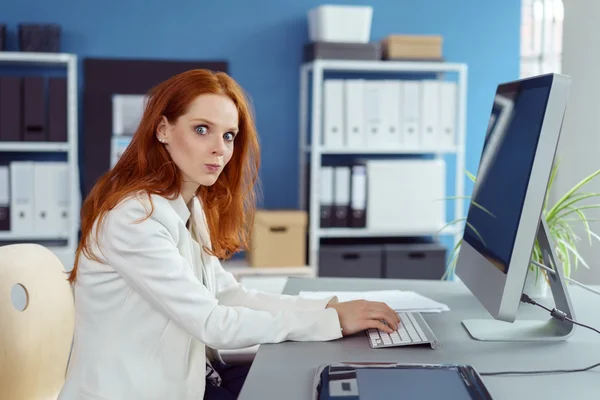 Woman with puckered lips typing on computer — Stock Photo, Image