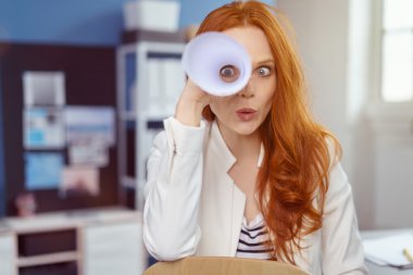 Playful young businesswoman spying on the camera clipart