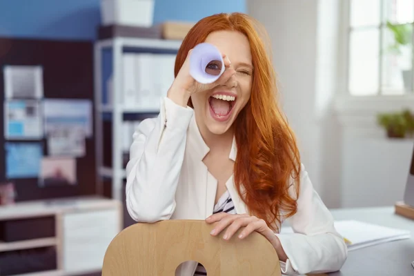 Rindo mulher olhando através de rolo de papel — Fotografia de Stock