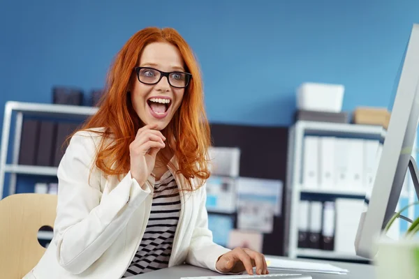 Opgewonden jonge vrouw die werkt bij Desk op computer — Stockfoto