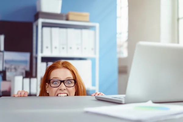 Junge Geschäftsfrau beißt auf ihren Schreibtisch — Stockfoto