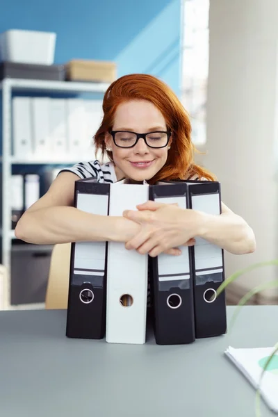 Mujer con los ojos cerrados abrazando carpetas portátiles — Foto de Stock