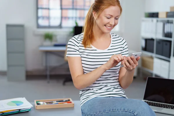 Lächelnde junge Designerin checkt ihr Handy — Stockfoto