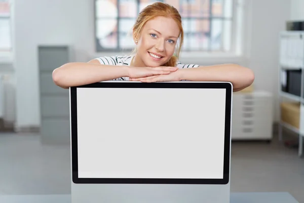 Happy smile woman leaning on a computer monitor — Stok Foto