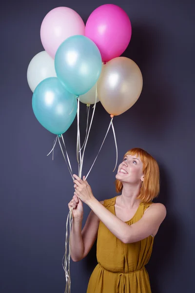 Happy young woman holding aloft party balloons — Stock Photo, Image