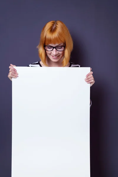 Attraente donna sorridente che tiene un segno in bianco — Foto Stock
