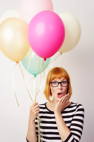 Surprised young woman holding a bunch of balloons — Stock Photo, Image