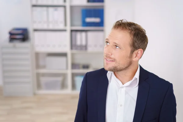 Thoughtful businessman standing in an office — Stock Photo, Image