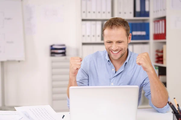 Empresário feliz que reage a notícias no computador portátil — Fotografia de Stock