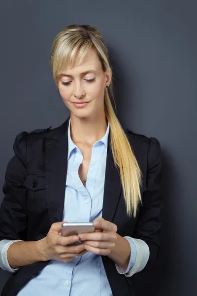 Grinning woman using phone over dark background — Stock Photo, Image