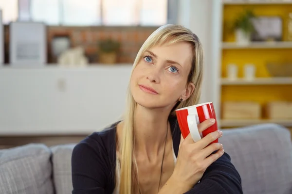 Woman sitting daydreaming over a mug of coffee — Stock Fotó