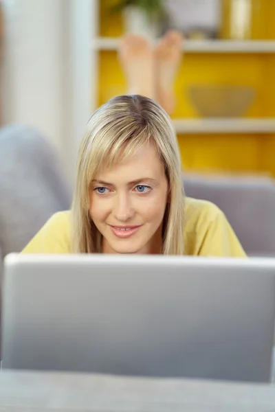 Mulher sorrindo usando laptop no sofá — Fotografia de Stock
