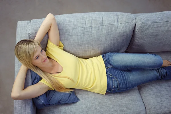 Giovane donna che riposa in poltrona grigia — Foto Stock