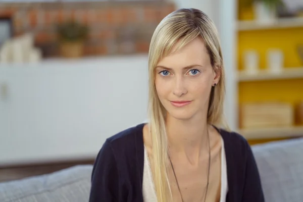 Grinsende junge Frau auf grauem Sofa — Stockfoto