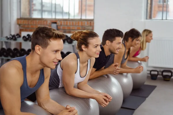 Five men and women on yoga balls by window