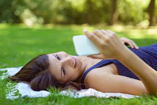 Relaxado jovem mulher mentindo lendo suas mensagens — Fotografia de Stock