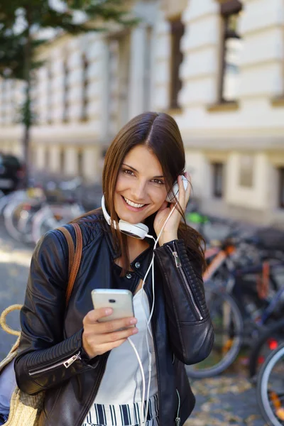 Young woman listening to headphones while standing — Stock fotografie