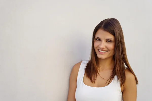 Beautiful woman in white near wall — Stock Photo, Image