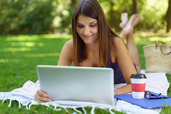 Donna sdraiata davanti al portatile fuori — Foto Stock