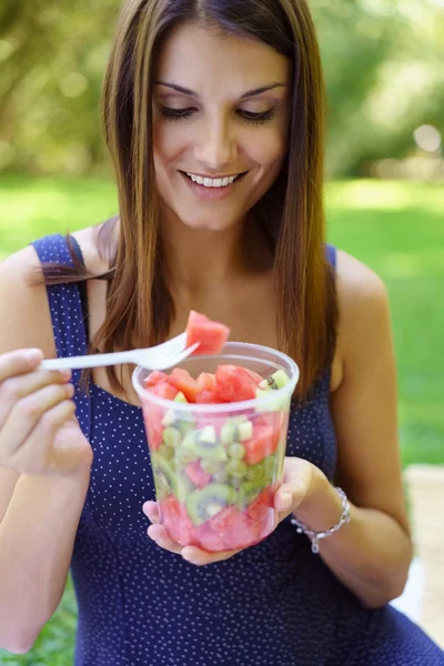 Mulher feliz saudável comendo uma salada de frutas frescas — Fotografia de Stock