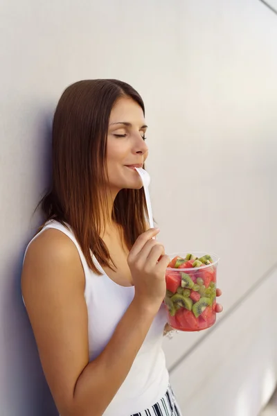 Genç kadın bir ağız dolusu meyve salatası tadını çıkarıyorlar — Stok fotoğraf