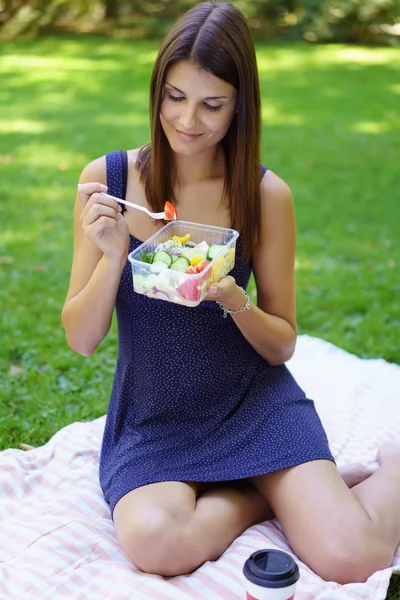 Όμορφη νεαρή γυναίκα που κάθεται στο πετσέτα τρώει — Φωτογραφία Αρχείου