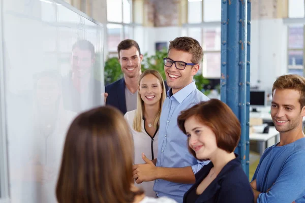 Sonriente hombre escribiendo de pie cerca de la junta en la reunión — Foto de Stock