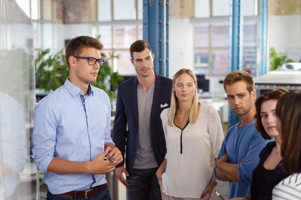 Serieuze arbeiders staan rond whiteboard — Stockfoto