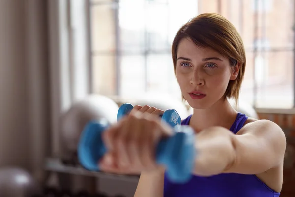 Vrouw met uitgestrekte arm houdt gewichten — Stockfoto