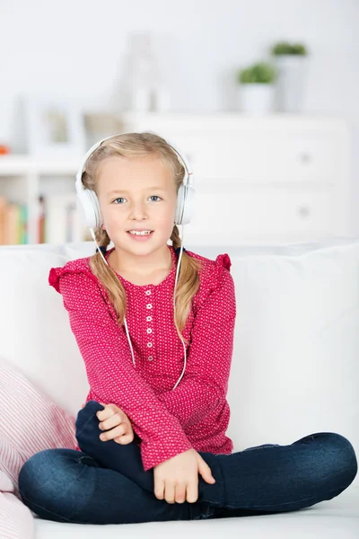 Girl with headphones sitting on sofa — Stock Photo, Image