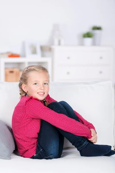 Sorridente bambina seduta sul divano — Foto Stock