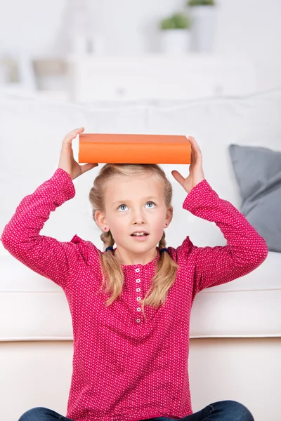 Girl balancing book on head — Stock Photo, Image