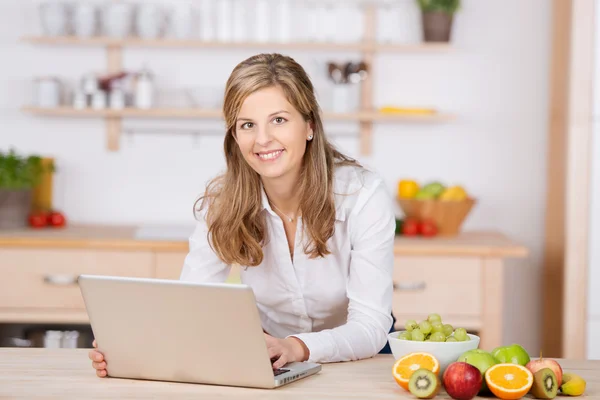 Woman with laptop in kitchen — Stock Photo, Image