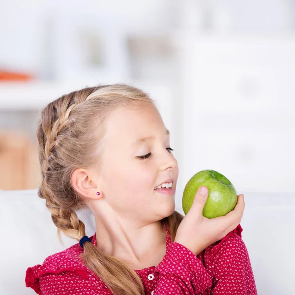 Colegiala mirando verde manzana fresca — Foto de Stock