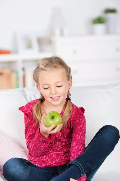 Menina olhando sorrindo para maçã verde — Fotografia de Stock