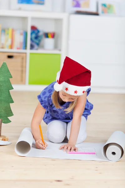 Mädchen mit Weihnachtsmütze schreibt Wunschliste — Stockfoto