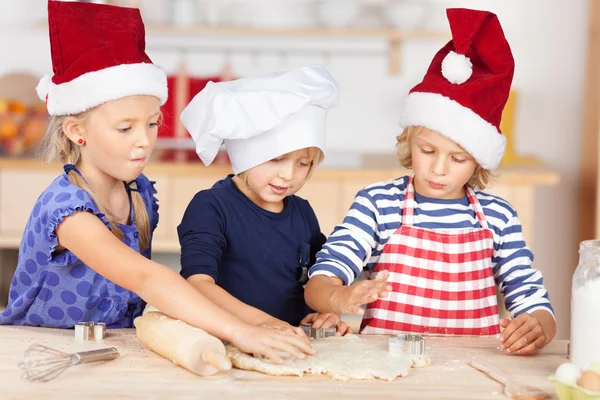 Little girl using cookie cutters on dough — Stock Photo, Image