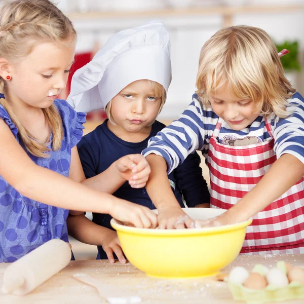 Girl pouting while sisters making dough — Stock Photo, Image