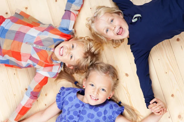 Petits frères et sœurs couchés sur le plancher de bois franc — Photo